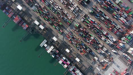 Large-Container-Ship-docked-at-Hong-Kong-commercial-port,-top-down-aerial-view-including-Stacks-of-Shipping-containers-on-a-holding-platform