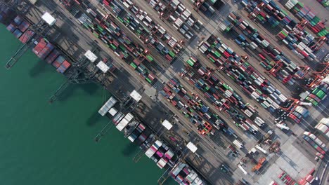 large container ship docked at hong kong commercial port, top down aerial view including stacks of shipping containers on a holding platform