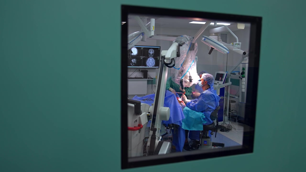 Operación neuroquirúrgica bajo microscopio realizada por el cirujano. Vista a través de la ventana de la puerta de un quirófano