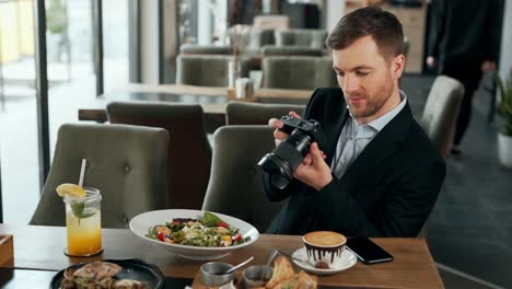 stylish adult man takes pictures on a mirrorless camera dishes in a restaurant