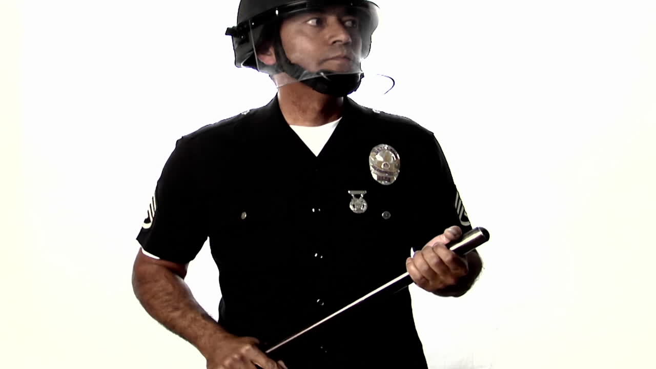 un oficial de policía con equipo antidisturbios desliza un bastón de un lado a otro