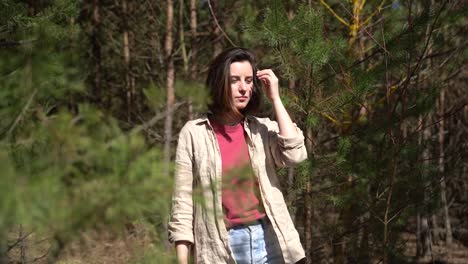 a young beautiful brunette girl walks through a pine forest.