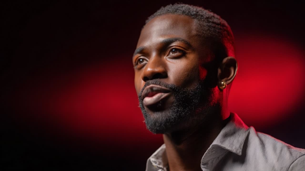 A dynamic close-up of a man passionately expressing himself, captured in a well-lit studio setting with striking red background, showcasing his confidence and engagement with the audience