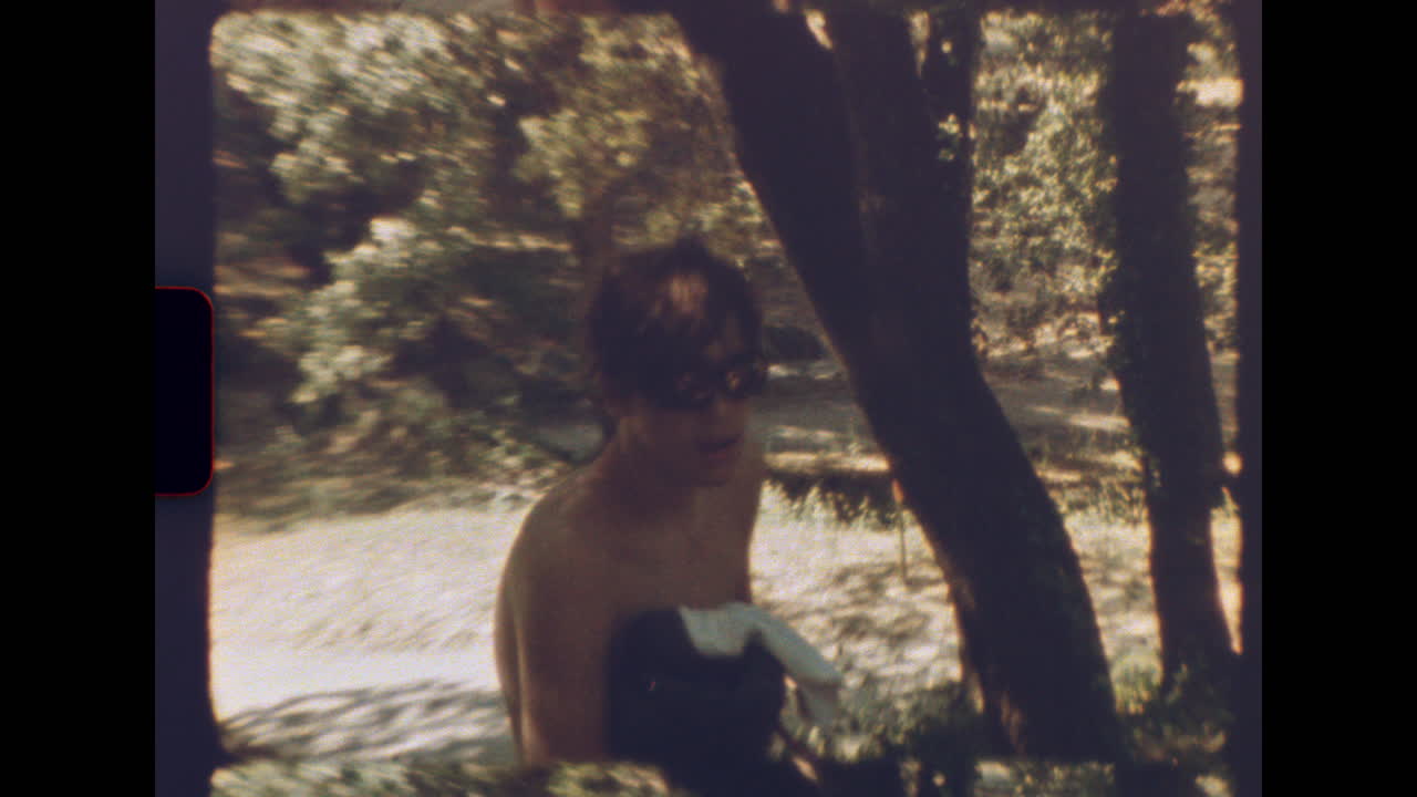 Retro 8mm scene of shirtless boy walking through summer forest