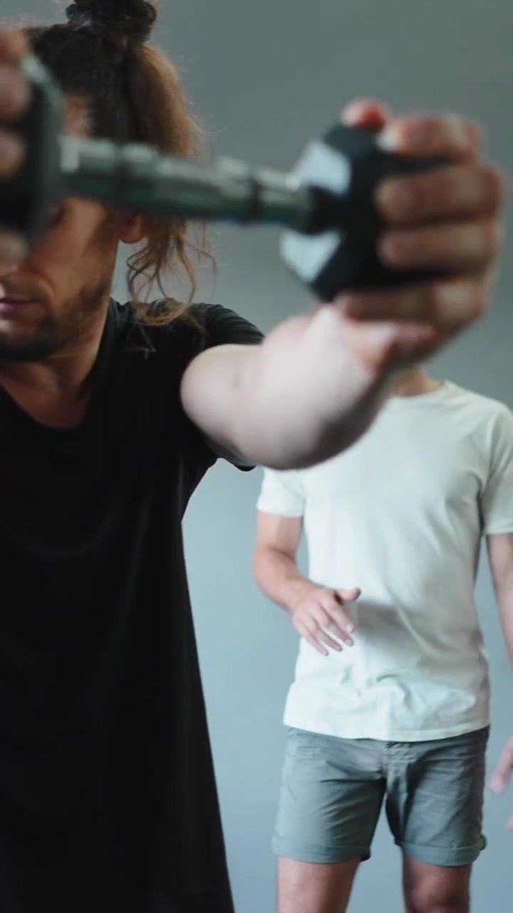 Personal trainer che istruisce il cliente su un esercizio con manubri