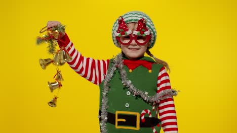 niña niña en navidad elf santa ayudante disfraz sosteniendo y sonando campanas juguete. vacaciones de año nuevo