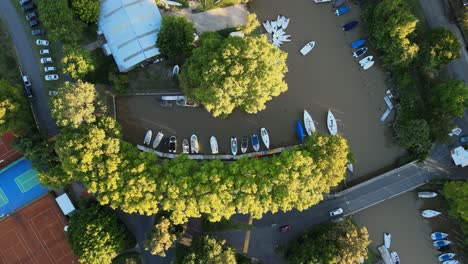 Aerial-top-down-view-of-boats-docked-in-a-nautical-club-revealing-some-tennis-courts