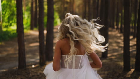 Lady-in-wedding-dress-runs-holding-chiffon-skirt-in-forest