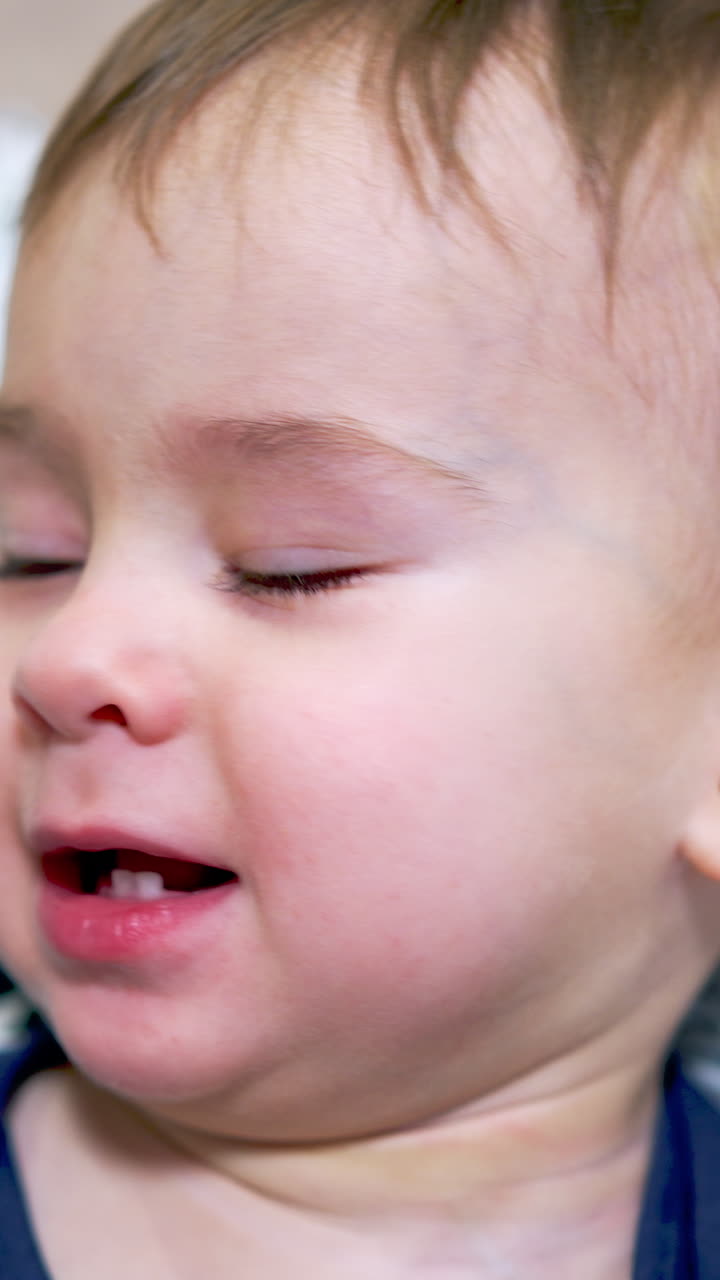 Little adorable toddler lies on the soft fluffy pillow. Portrait of a cute Caucasian baby boy close up. Vertical video