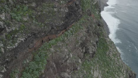 un grupo de excursionistas caminan al borde de la montaña quebrada do negro en madeira