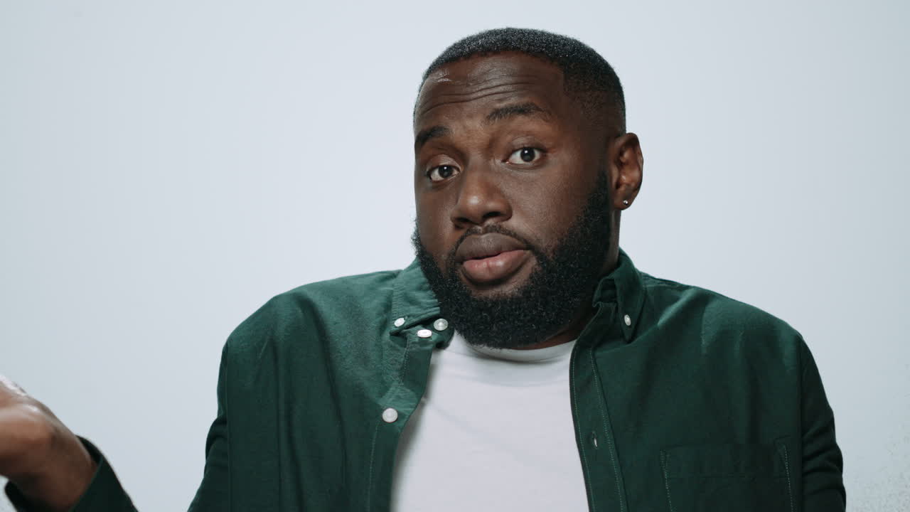 Portrait of african american man showing dont know gesture on grey background.