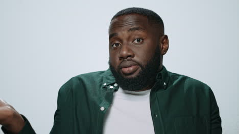 portrait of african american man showing dont know gesture on grey background.