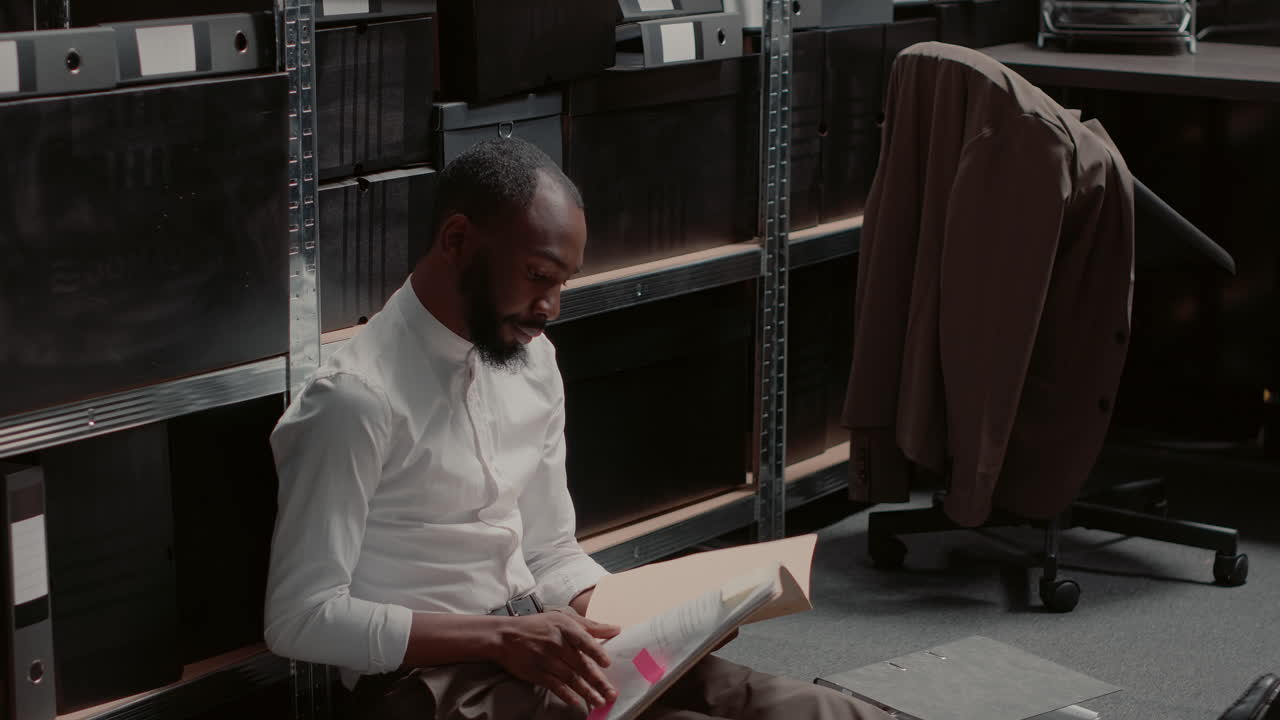 Man sitting on office floor near filing cabinets
