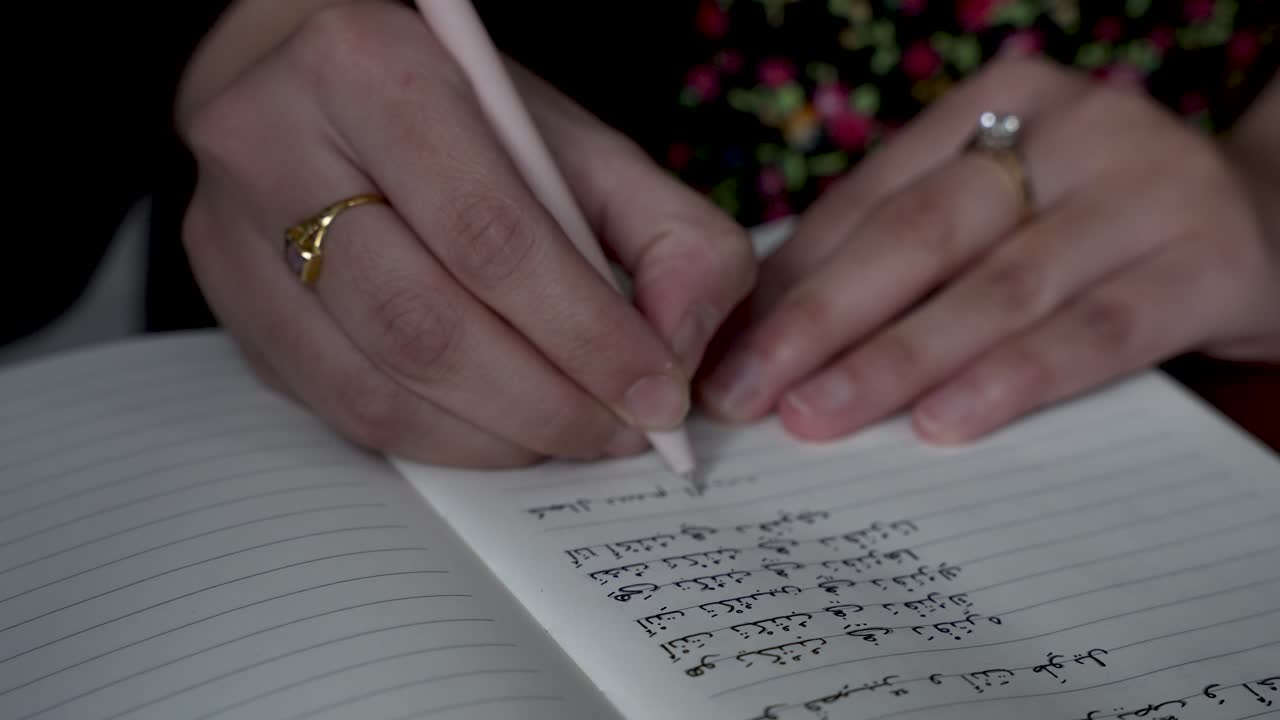 Person practices writing Arabic letters in a notepad, highlighting the concept of learning and mastering letters in a different language