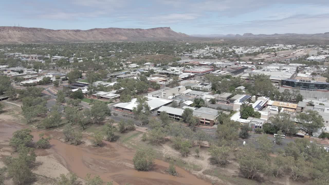 Alice Springs Remote Town With Muddy Water Flower At Todd River During Daytime - Heavitree Gap In MacDonnell Ranges, Northern Territory, Australia. - aerial