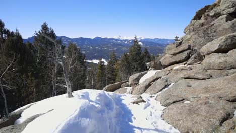 snowy hiking trail through rocky terrain with mt evans in the distance, colorado