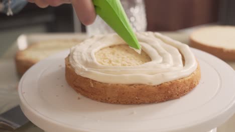 close-up scene of a woman who is putting white cream on a biscuit with a confectionery syringe