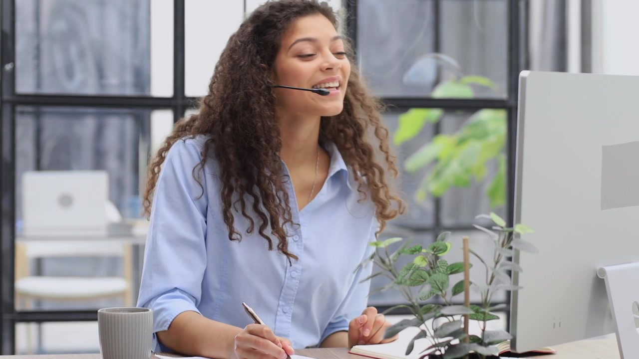 Jovem Mulher com Headset Falando e Escrevendo Durante Chamada de Vídeo