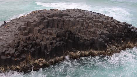 ocean waves hitting a unique hexagonal rock structure