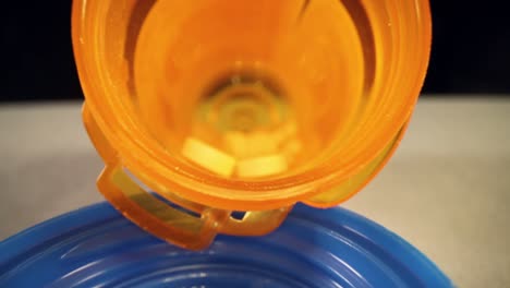 speeding past empty bottle cap, very slowly pushing into the length of a prescription pill bottle, shallow focus to reveal details