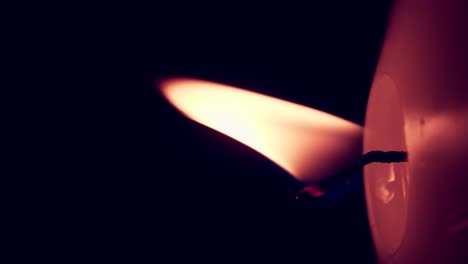 vertical rotation of single big yellow candle flame lights isolated on a black background