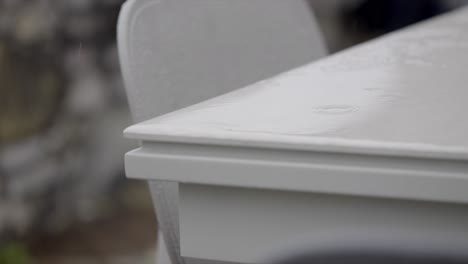 Raindrops-falling-on-plastic-garden-patio-furniture-close-up-Slow-motion