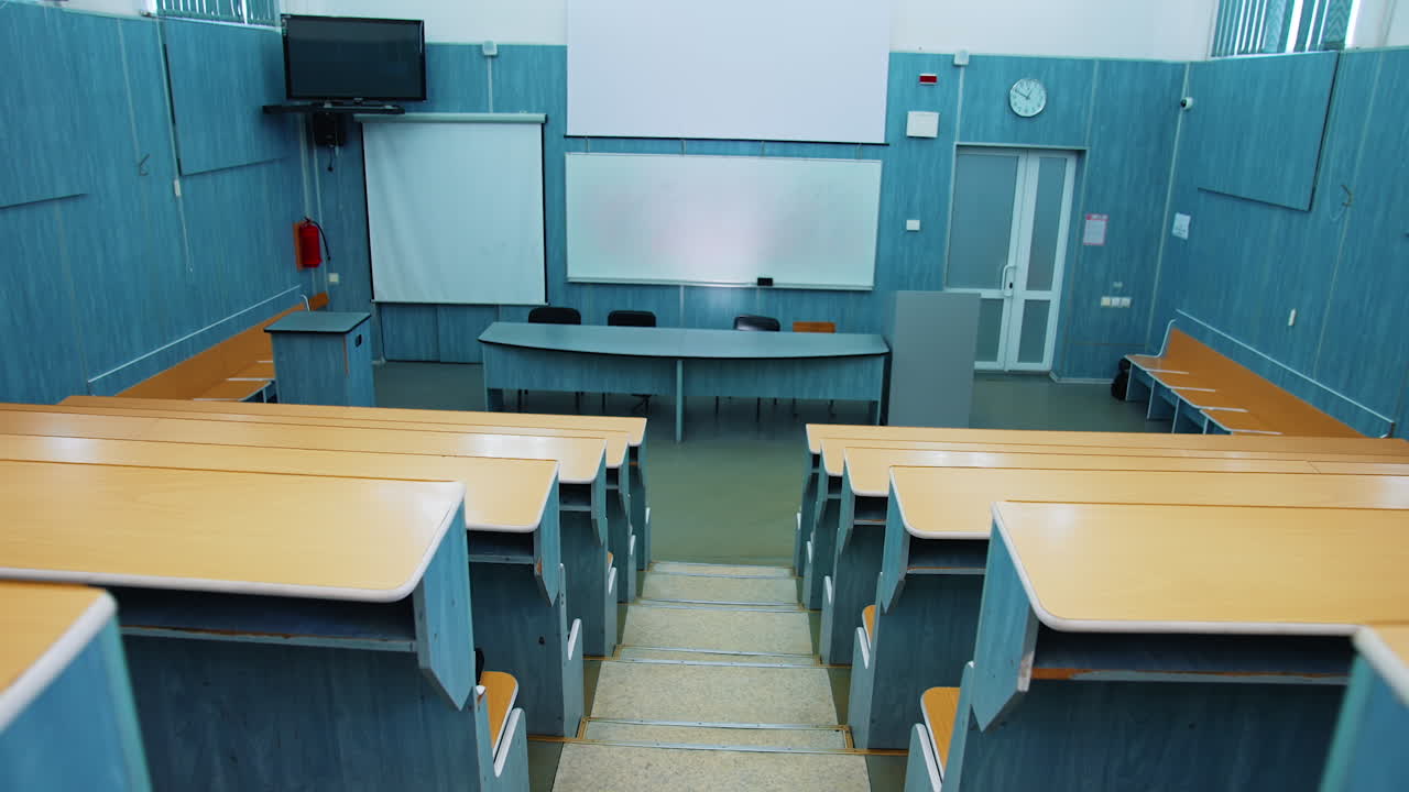 Empty auditorium. Modern lecture hall in the university. Wooden desks in front of blackboard and multimedia board in conference hall.