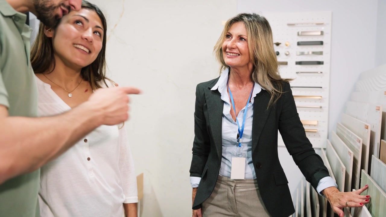 Vendedora asesorando a una pareja sobre la selección de azulejos en la sala de exposición