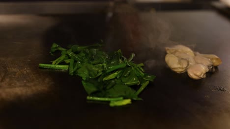 spinach wilting and oysters cooking on hot pan