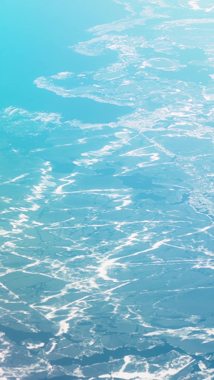 ヘルシンキ近郊の空撮。明るい冬の光の中で飛行機から撮影された、氷に覆われたバルト海の水面と凍結した沿岸の入り江。抽象的な北欧の模様が特徴。