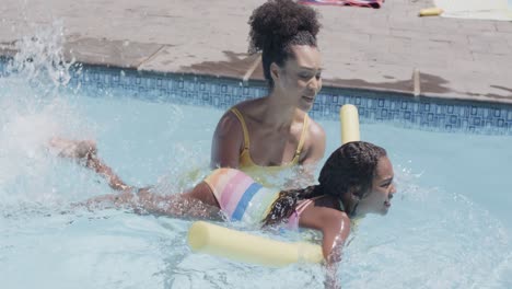 Happy-african-american-mother-and-daughter-having-swimming-lesson-in-swimming-pool,-slow-motion