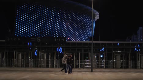 night view of a modern arena with people walking towards the entrance