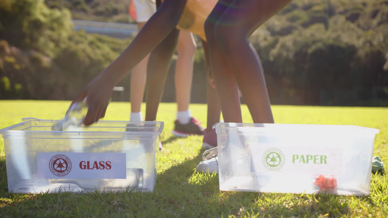Recycling at school, girls sorting glass and paper into separate bins