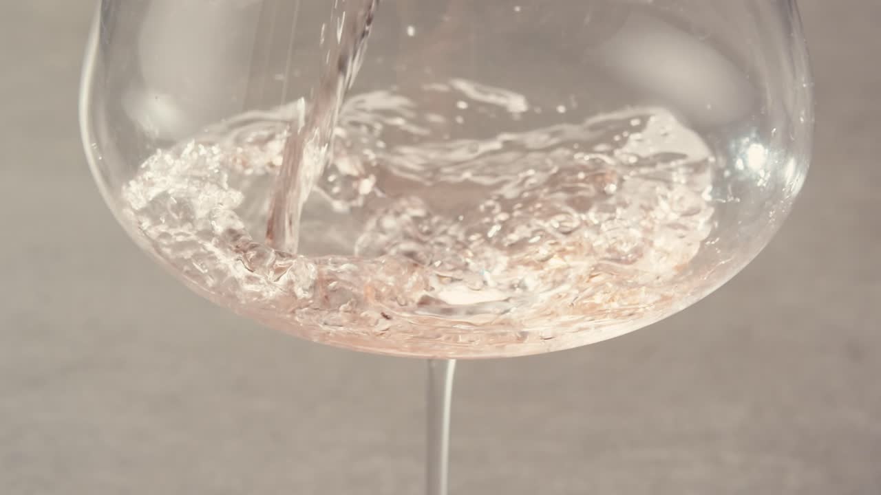 Orange or white wine bottle and glass against a sunset in a peaceful vineyard, pouring of ecological natural wine.