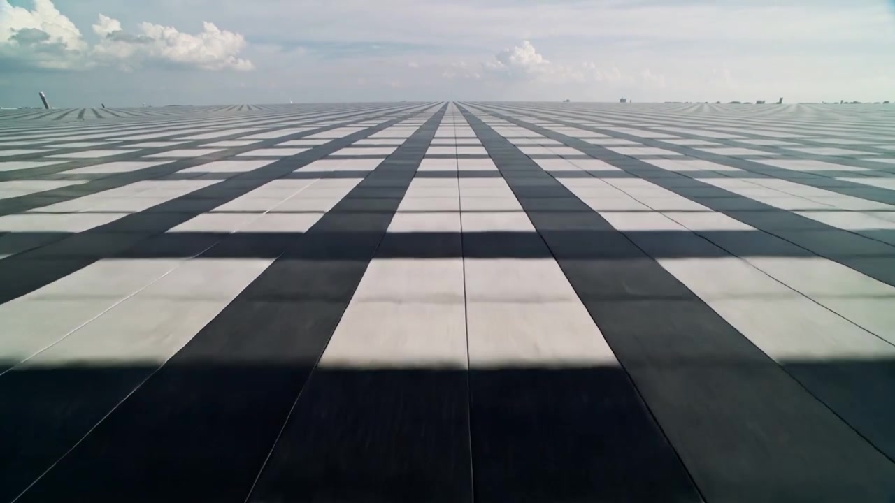 Framåtrörlig kamera som glider över ett centrerat konvergerande panelnät på ett stort tak, visar en skiftande skugga.