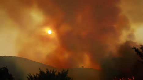 a striking visual of wildfire smoke eclipsing the sun, creating an eerie atmosphere as orange and yellow hues paint the sky in a dramatic display of nature's fury