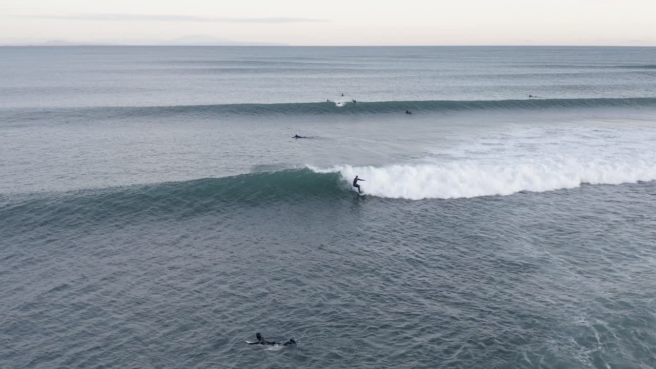 largas olas ruedan hacia la costa de islandia con surfistas desafiando el agua fría, antena