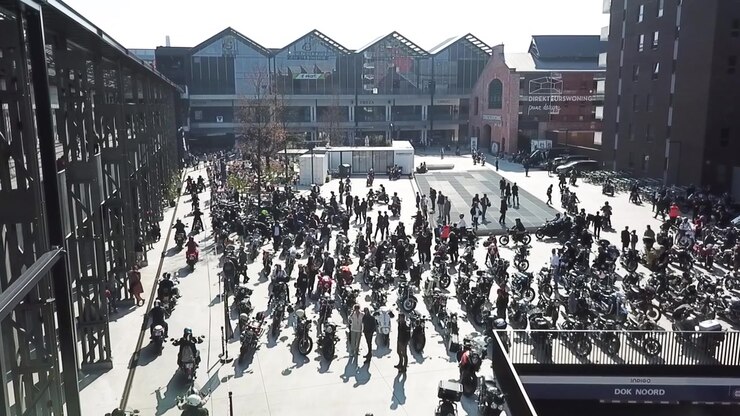 Steady drone shot of people arriving at the end of the Distinguished Gentlemans Ride in Ghent Belgium. Aerial view.