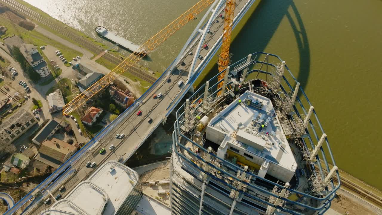 la grúa amarilla construye un rascacielos en el sitio de construcción por encima de la autopista ocupada en un día soleado