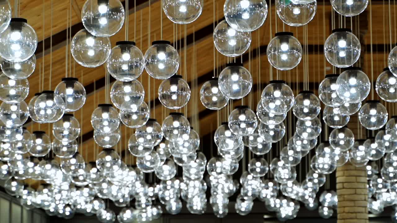 Luxury interior of sparkling lamps. Blurred view of modern ceiling lighting of hanging light bulbs balls indoors.