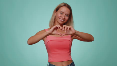 una hermosa mujer sonriente hace un gesto de corazón demuestra un signo de amor expresa buenos sentimientos y simpatía