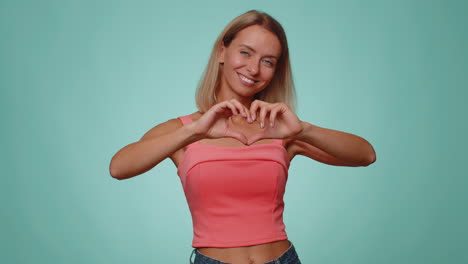 smiling pretty woman makes heart gesture demonstrates love sign expresses good feelings and sympathy