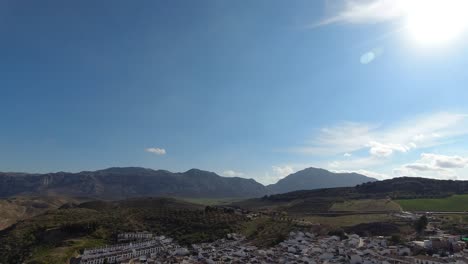 Panoramic-view-over-rural-countryside-with-few-houses-and-mountains-in-distance