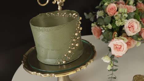 close up of a modern green wedding cake with gold pearls on a stylish cake stand