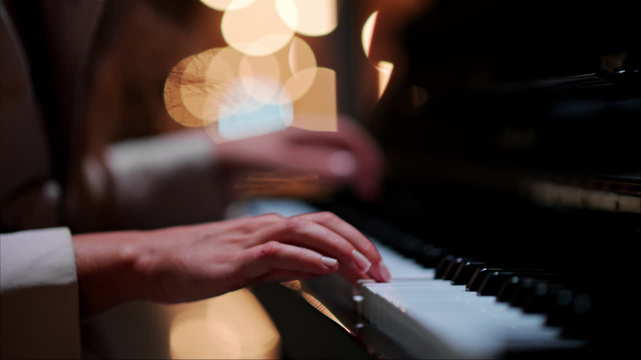 Close up of a woman's hands playing the piano with blurry lights on the background