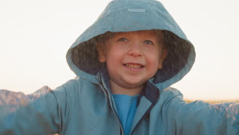 boy stands delighting in warmth of rain closeup happy child giggles with glee embracing pouring rain