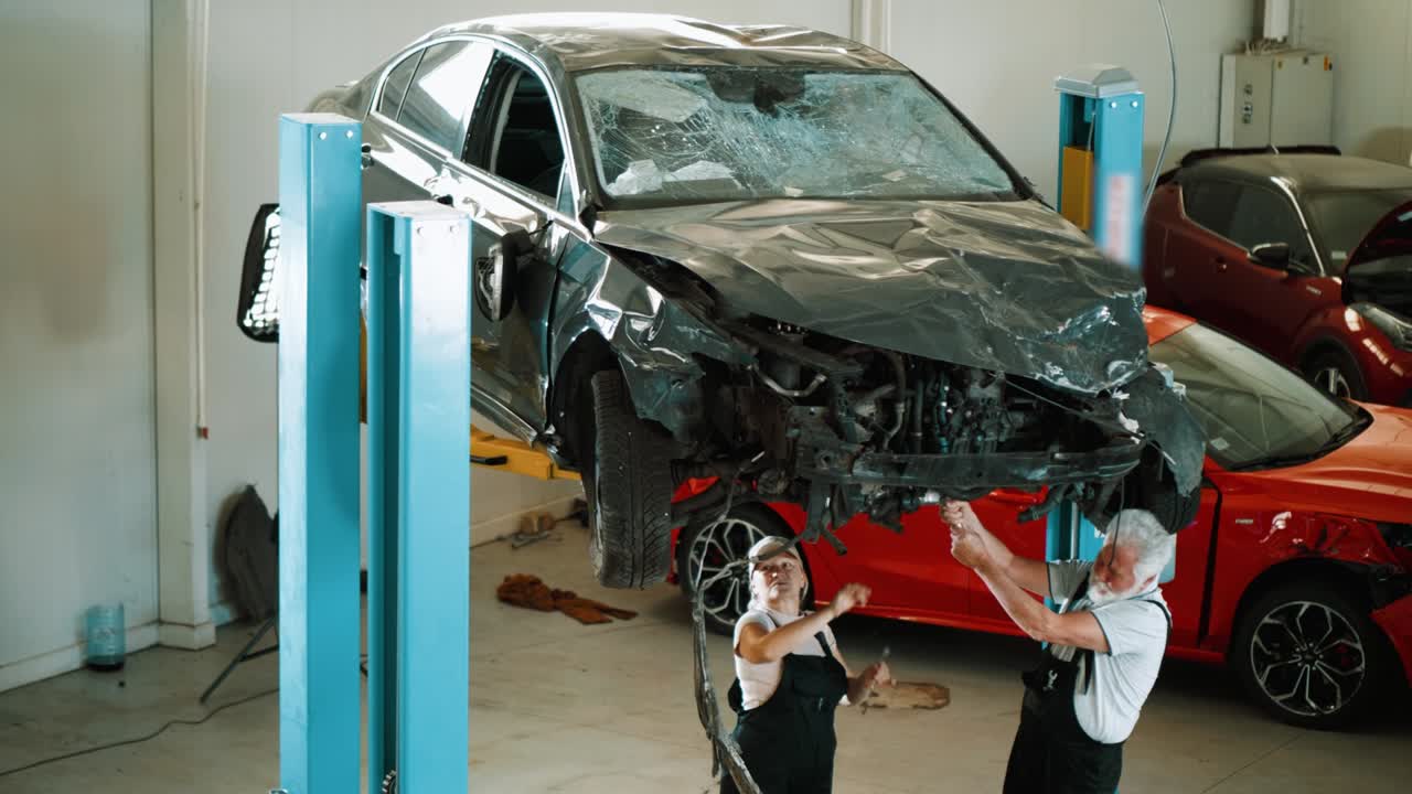 automóvil dañado en una máquina de elevación de automóviles en un taller. mecánicos de automóviles trabajando debajo del automóvil en el garaje