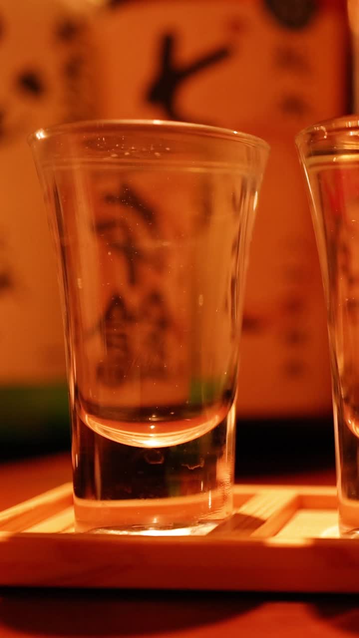 나무 로 된 받침대 에 사케 컵 을 채우고 있다