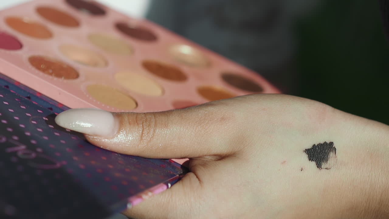 un artista de maquillaje con un punto en la mano sostiene una paleta de sombras de ojos