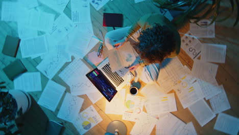 woman working with financial documents and laptop during night